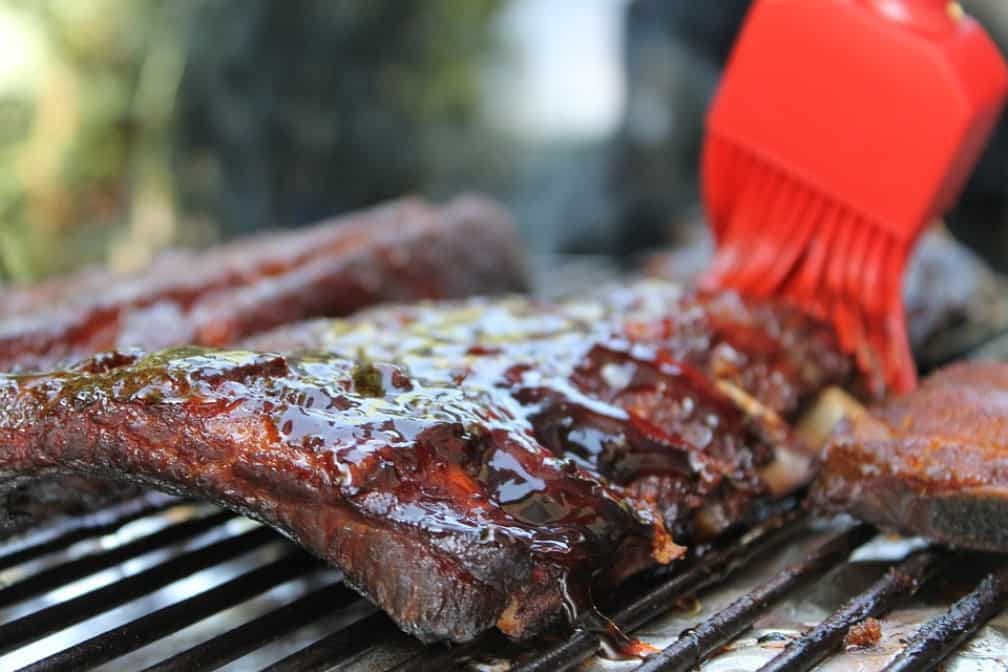 Best BBQ in Kansas City - ribs on a grill being brushed with sauce