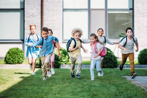 Back to School in Kansas City - six kids running across the playground with backpacks and school bags