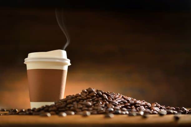 National Coffee Day - coffee in a paper to-go cup with a pile of coffee beans