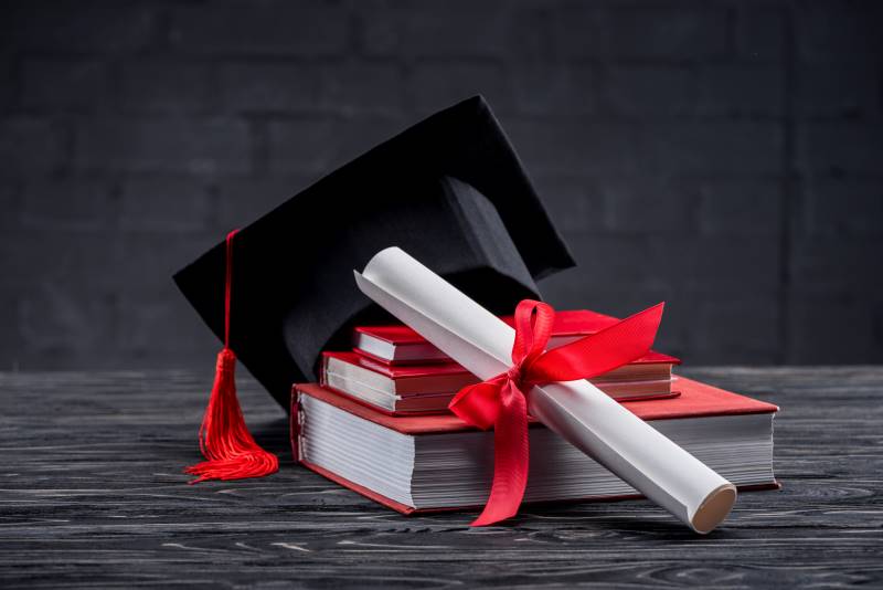 Freebies and Deals for Graduating Seniors in Kansas City  - image of graduation cap and diploma on a stack of books