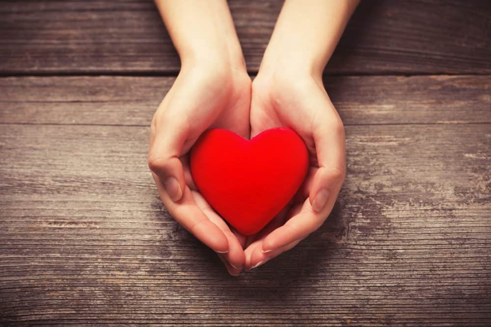 A hand holding a red stuffed fabric heart.